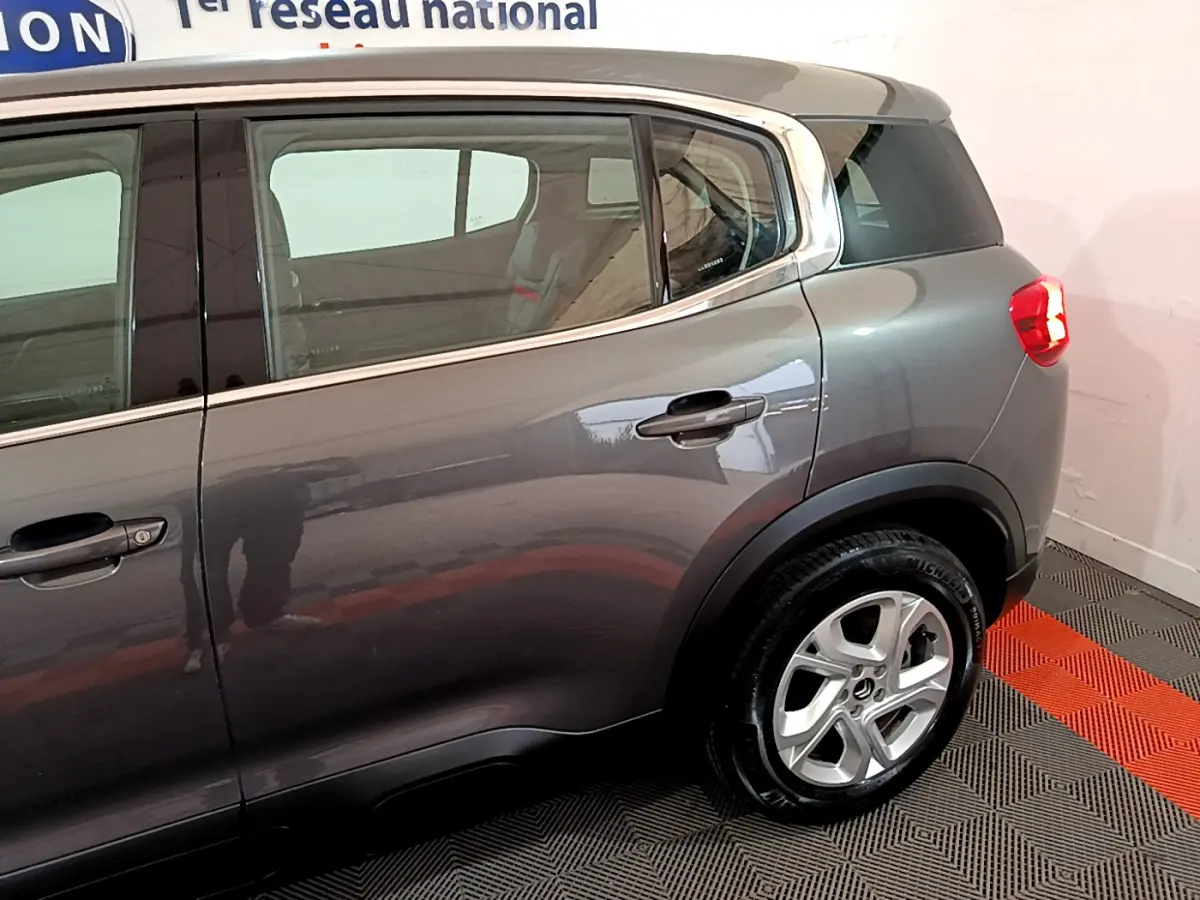 Vue côté droit arrière d'un Citroën C5 Aircross gris foncé avec jante alliage 17 pouces et vitres surteintées.