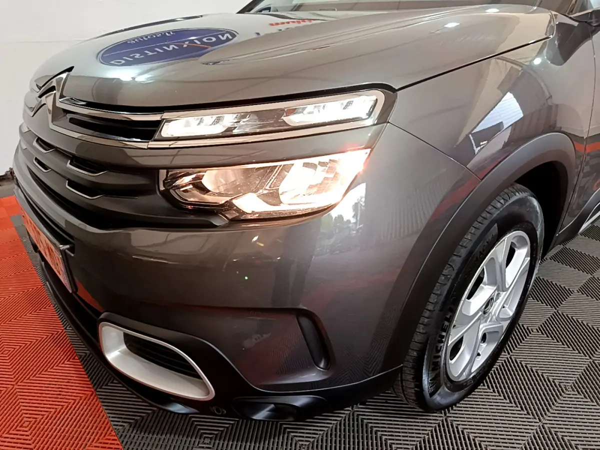 Vue 3/4 avant droit d'une Citroën C5 Aircross gris foncé avec feux allumés et jantes alliage 17 pouces.