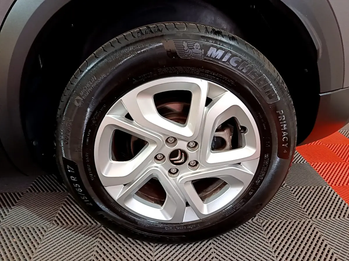 Gros plan sur la jante alliage 17 pouces argentée et pneu Michelin du côté avant droit du Citroën C5 Aircross gris foncé.