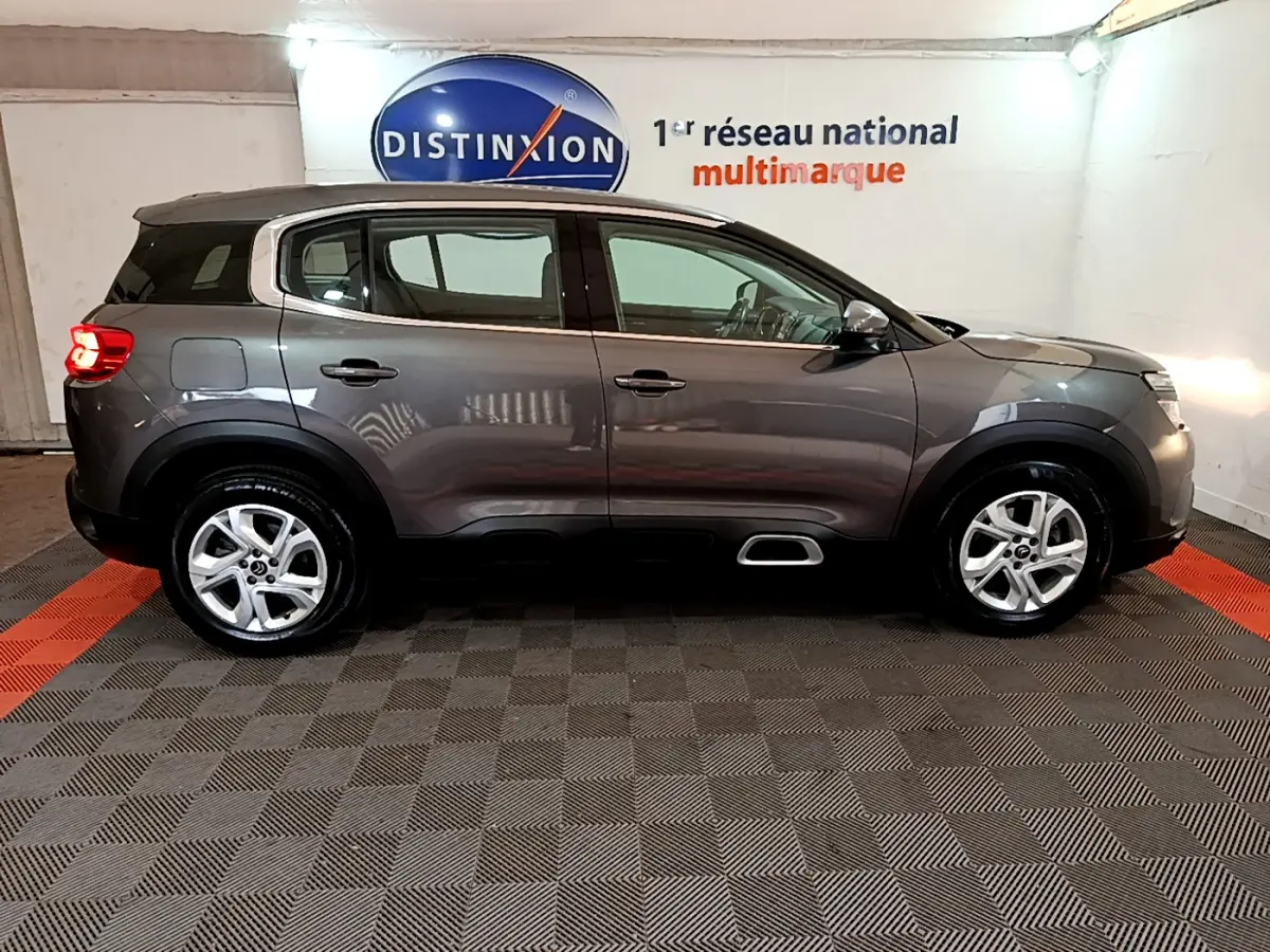 Vue de profil côté gauche d'un Citroën C5 Aircross gris foncé avec jantes alliage 17 pouces en intérieur showroom.