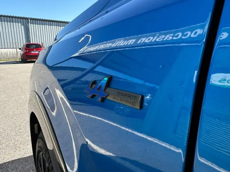 Gros plan sur l'aile avant gauche bleu sommet métallisé du Renault Rafale 1.2 E-Tech esprit Alpine avec logo Esprit Alpine.