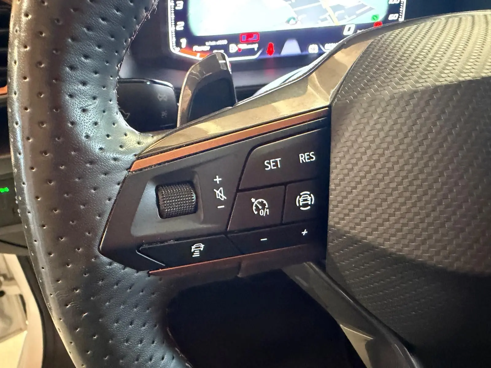 Gros plan sur les commandes de régulateur de vitesse au volant perforé d'une CUPRA LEON ST 2024, intérieur noir.