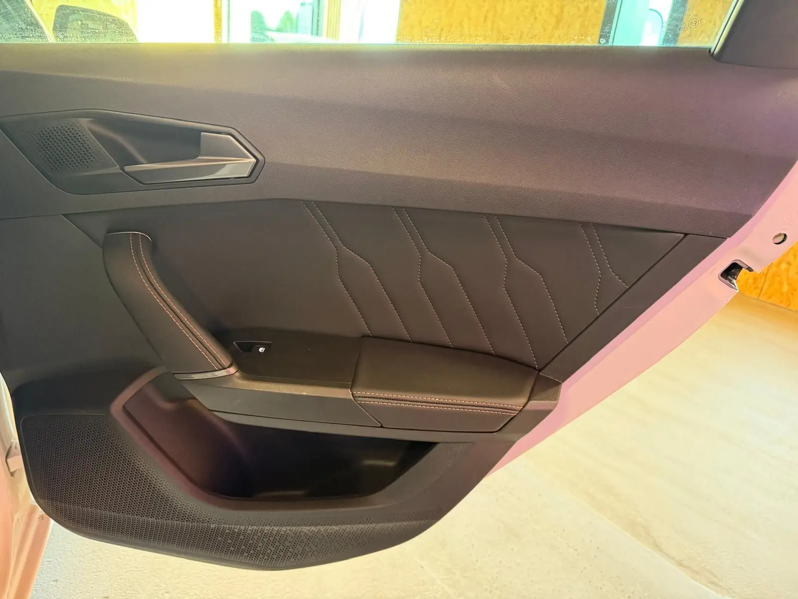 Vue intérieure côté gauche de la porte avant d'une CUPRA LEON ST blanche avec finition cuir noir et surpiqûres contrastées.
