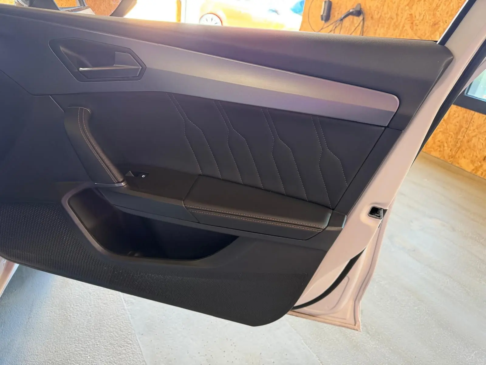 Vue intérieure de la porte avant droite blanche d'une CUPRA LEON ST 2024 avec garniture noire et surpiqûres contrastées.