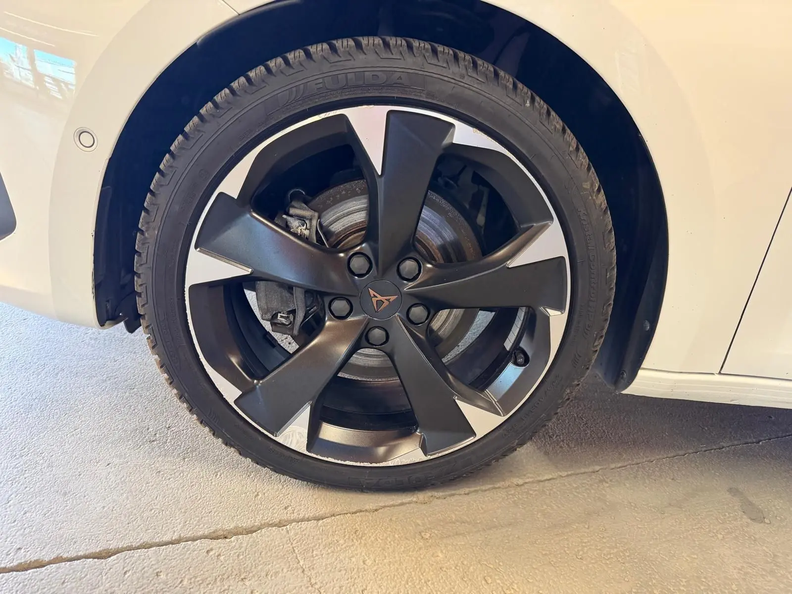 Gros plan sur la roue avant droite d’une CUPRA LEON ST blanche avec jante noire à cinq branches.