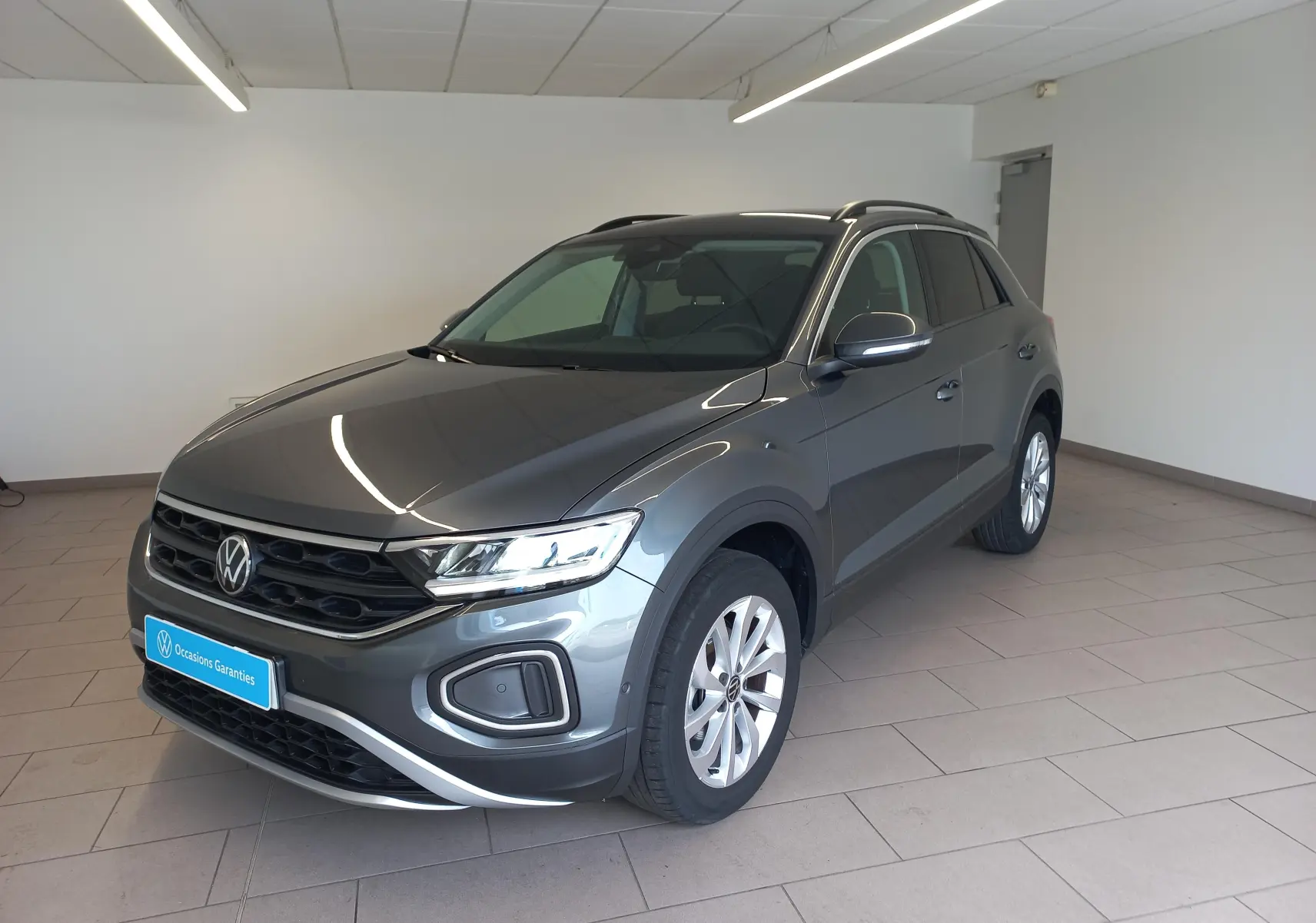 Volkswagen T-Roc 1.5 TSI 150 DSG7 VW Edition gris Indium, vue 3/4 avant droit en intérieur showroom.