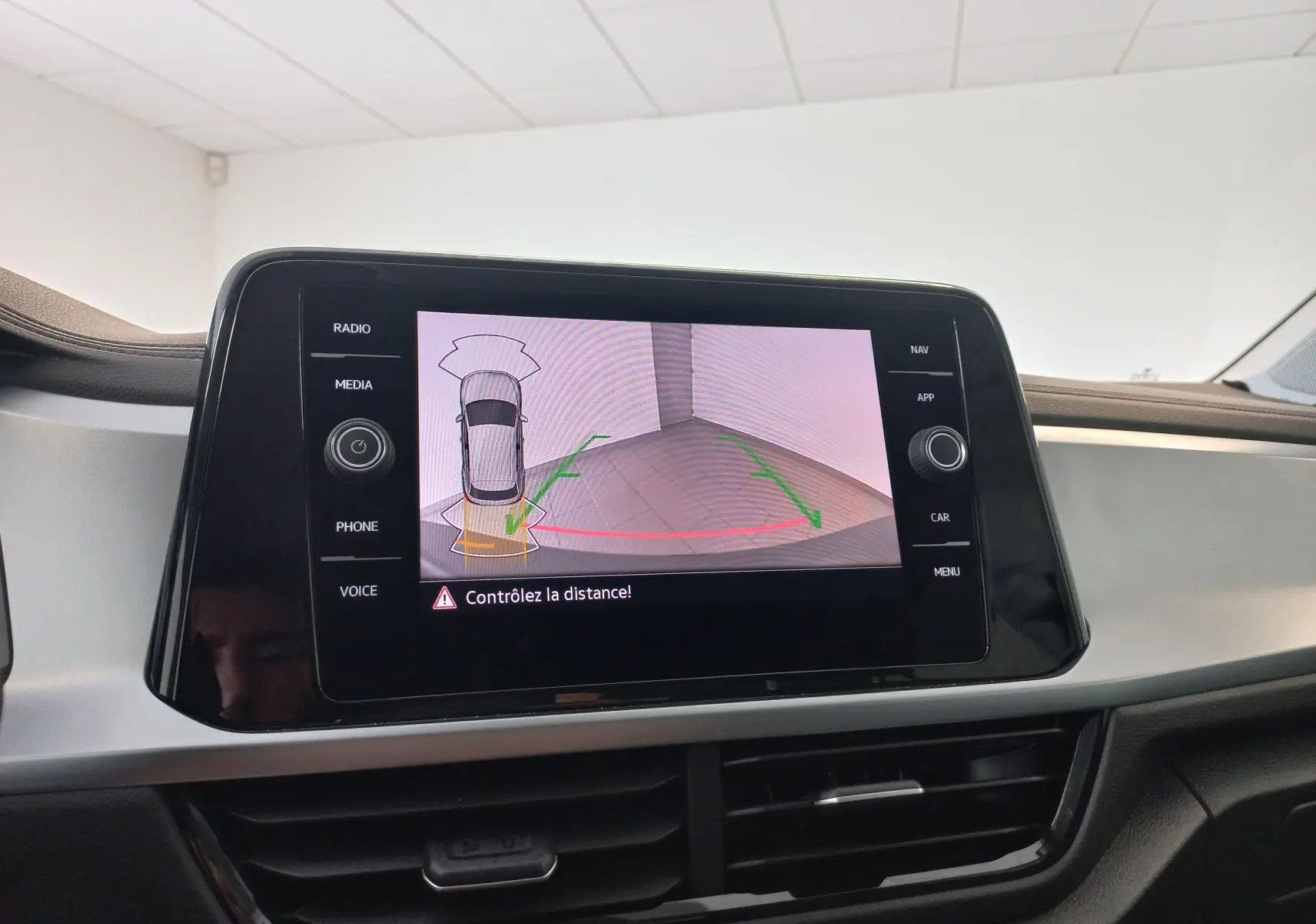 Écran central du Volkswagen T-Roc 2025 montrant la caméra de recul avec alertes de distance, intérieur gris et noir.