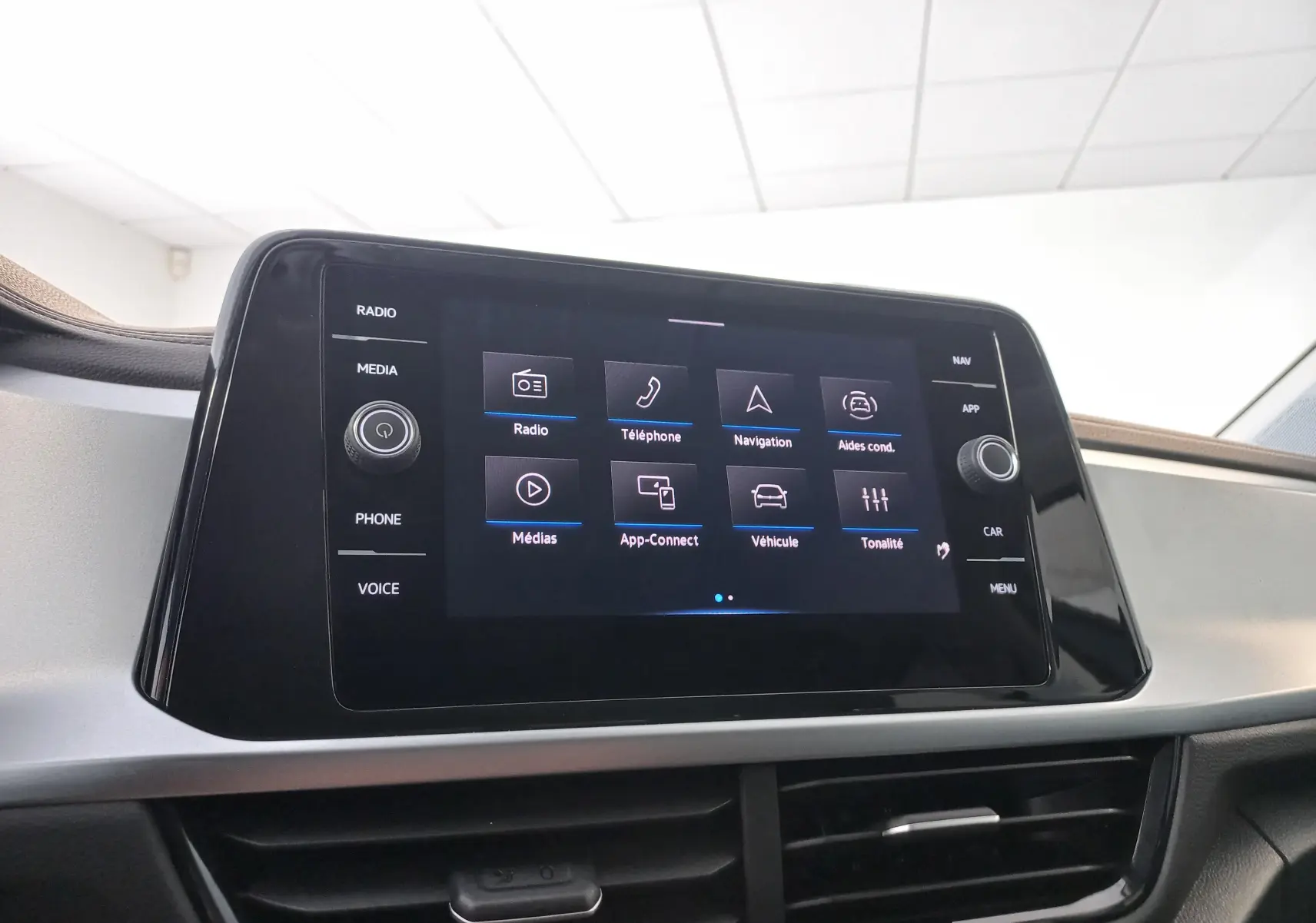Écran tactile central du Volkswagen T-Roc 2025 gris Indium, affichant le menu principal avec options multimédia et navigation.