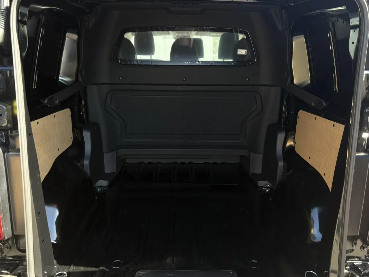 Vue intérieure arrière du Citroën Jumpy noir Perla, montrant l'espace de chargement vide et les panneaux latéraux en bois clair.