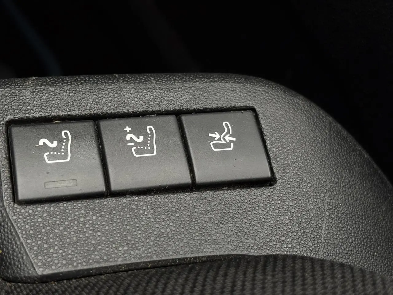 Gros plan sur les boutons de réglage des sièges chauffants et rabattables dans une Citroën C4 Spacetourer gris foncé.