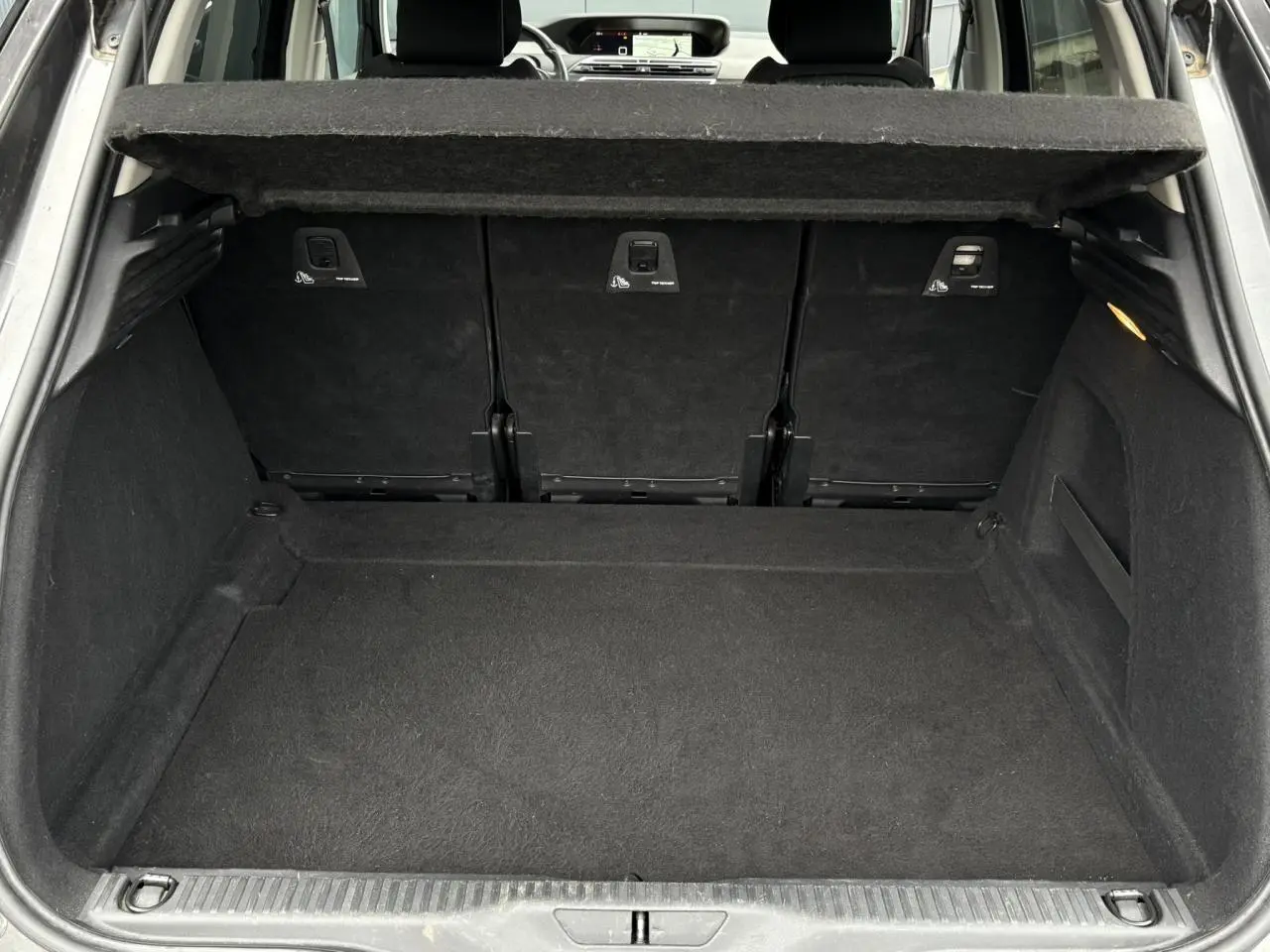 Coffre ouvert d'une Citroën C4 Spacetourer gris foncé, vue arrière montrant l'espace de chargement et la tablette de séparation.
