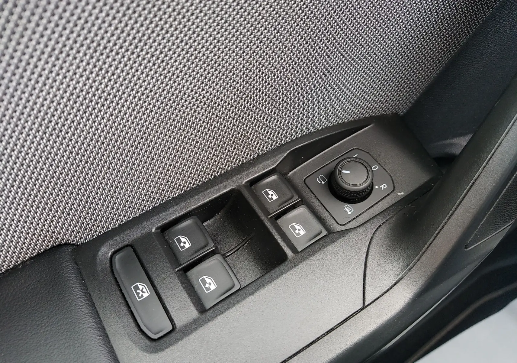 Gros plan sur les commandes de lève-vitres et réglage des rétroviseurs côté conducteur d’une SEAT Leon ST gris 2022.