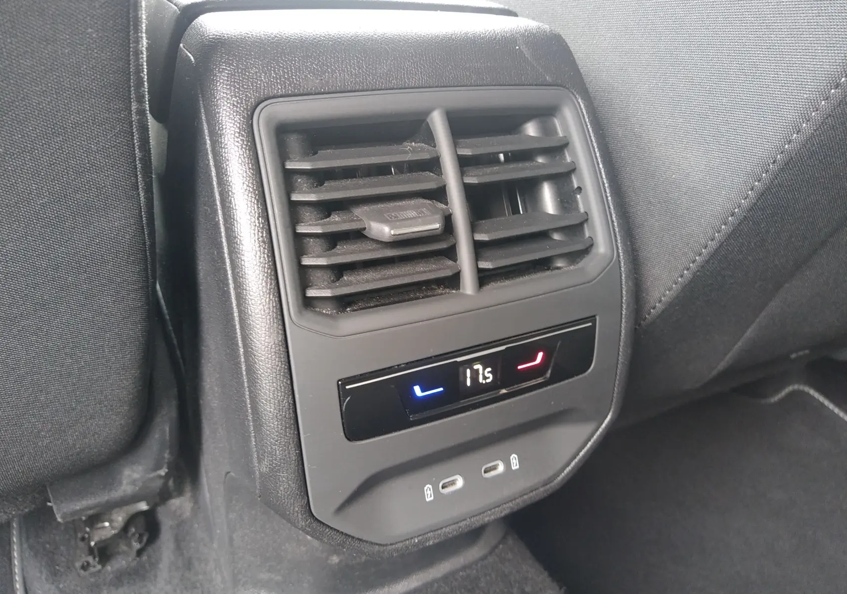 Gros plan sur la console arrière de la SEAT LEON ST grise 2022, avec bouches d’aération, affichage digital de la climatisation et ports USB.