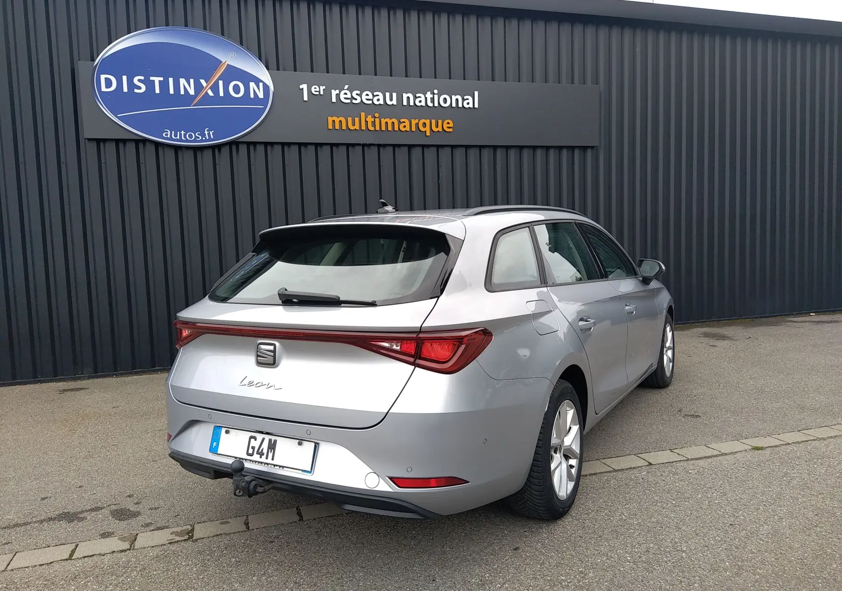 SEAT Leon ST gris vue 3/4 arrière droit, break avec attelage et feux arrière LED distinctifs.