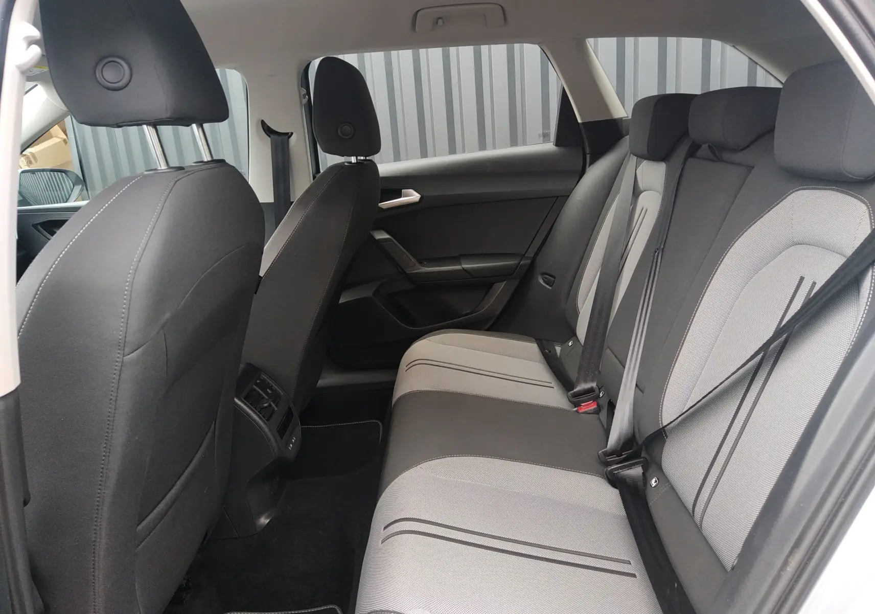 Vue intérieure côté droit des sièges arrière en tissu gris et noir de la SEAT LEON ST 2022, avec ceinture de sécurité visible.