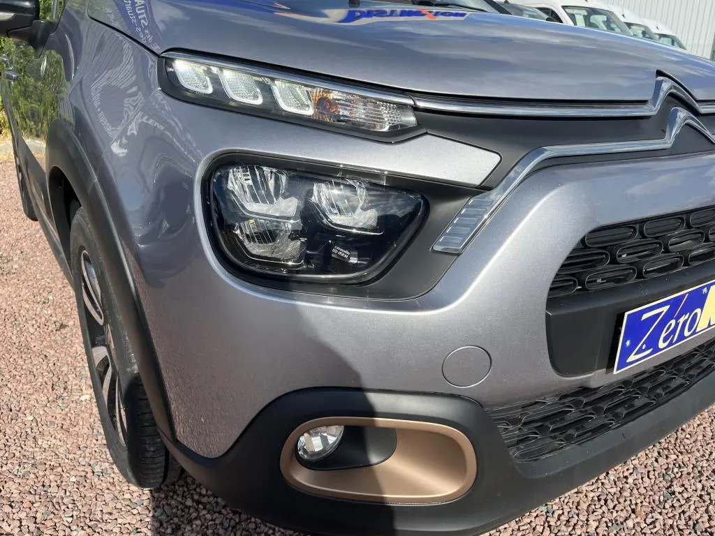 Gros plan sur l'avant droit gris métallisé d'une Citroën C3 2022, mettant en valeur ses phares LED et antibrouillard.