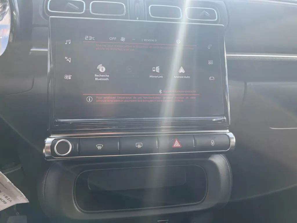 Écran tactile central avec commandes climatisation et alertes dans l'habitacle d'une Citroën C3 gris 2022.