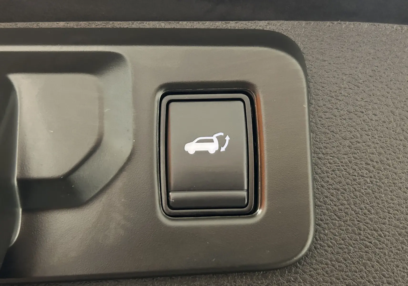 Bouton noir intérieur du hayon électrique avec pictogramme blanc d'ouverture sur Renault Symbioz E-Tech blanc nacré 2025.