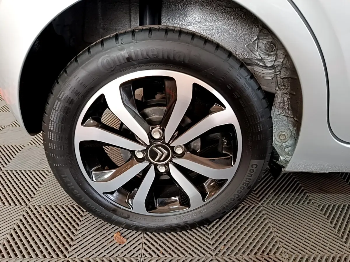 Gros plan sur la roue avant droite gris clair d'une Citroën C1 2019 avec jante alliage noire et argentée.