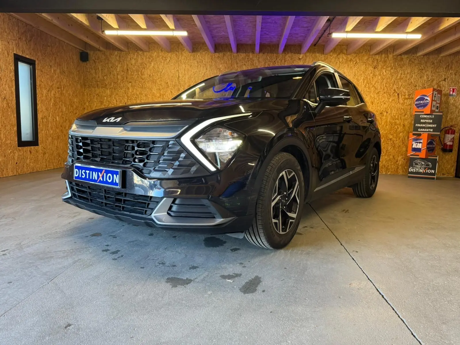 KIA SPORTAGE noir en 3/4 avant droit, mettant en valeur sa calandre distinctive et ses phares LED angulaires.