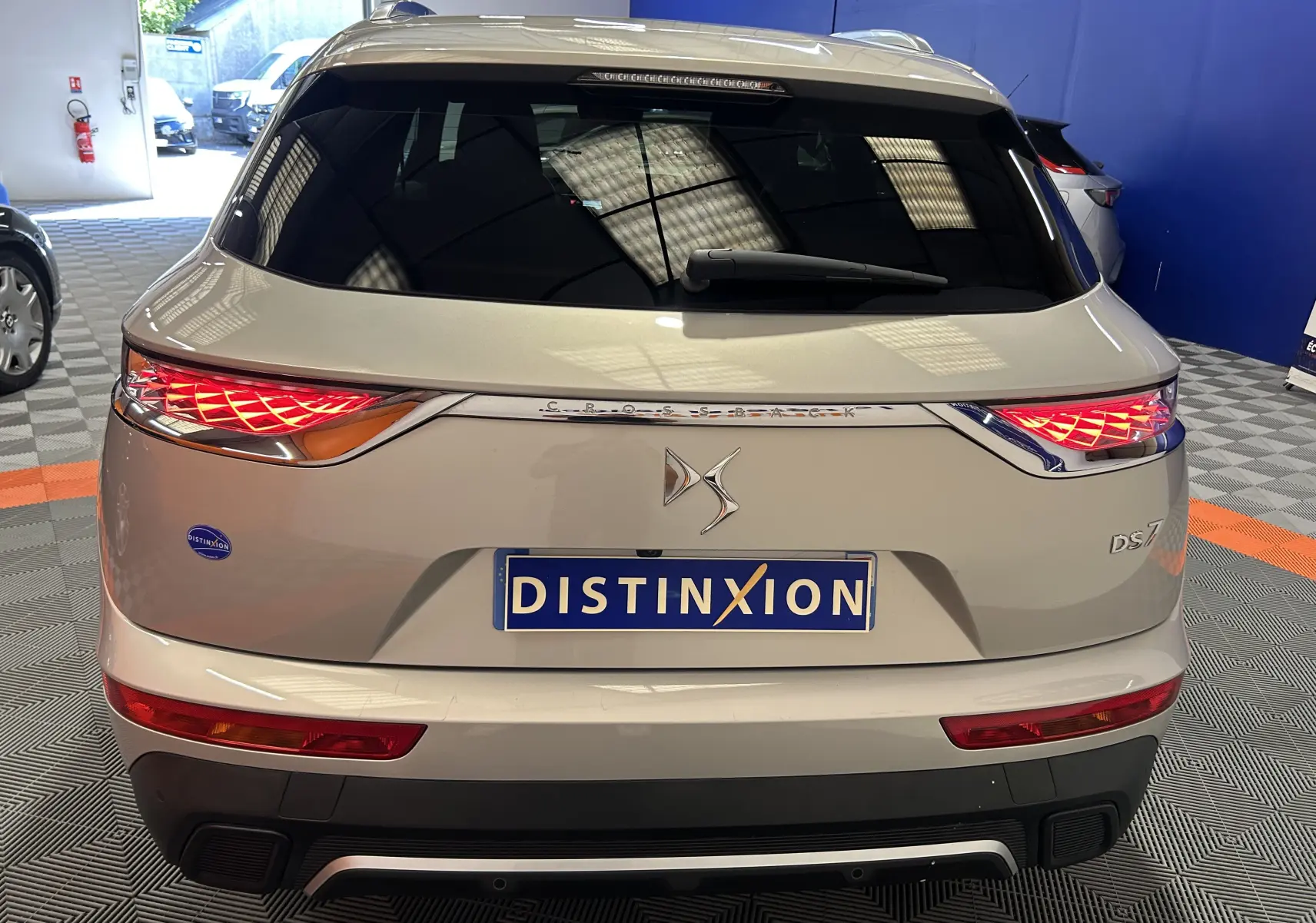 Vue arrière du DS7 Crossback bleu cristal pearl avec feux LED allumés dans un showroom.