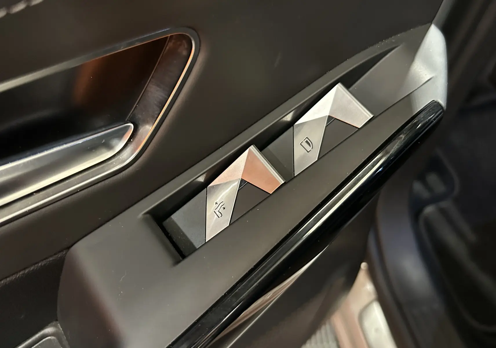 Gros plan sur les commandes des vitres électriques côté conducteur du DS7 Crossback bleu Cristal Pearl, intérieur noir.