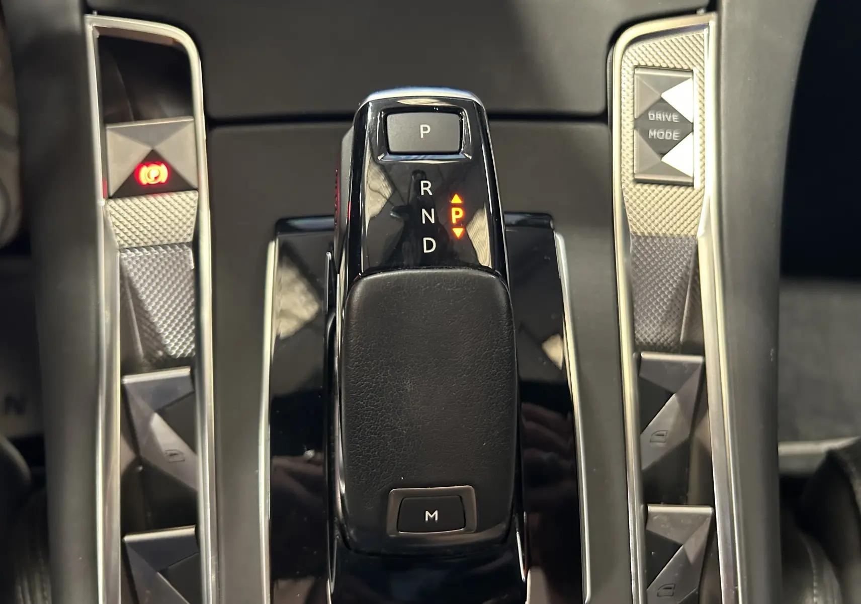 Gros plan sur la commande de boîte automatique noire du DS7 Crossback, avec boutons latéraux en finition argentée texturée.