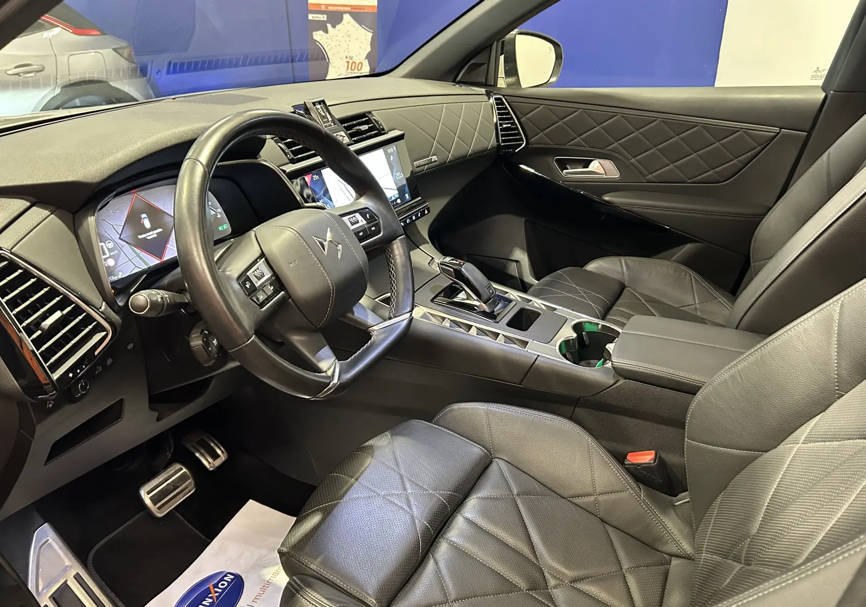 Vue intérieure côté conducteur du DS7 Crossback avec sellerie cuir noire matelassée et tableau de bord moderne.