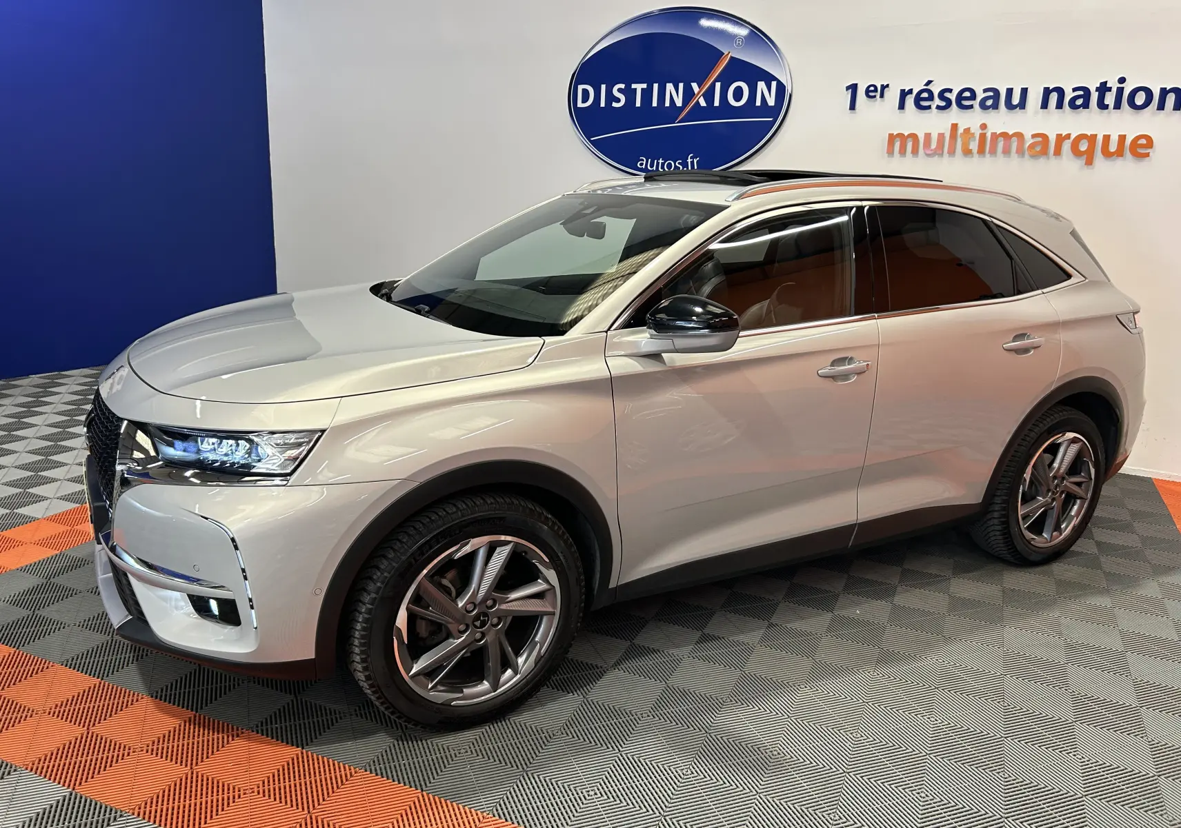 Vue 3/4 avant droit du DS7 Crossback bleu cristal pearl avec jantes alliage et vitres teintées en showroom.