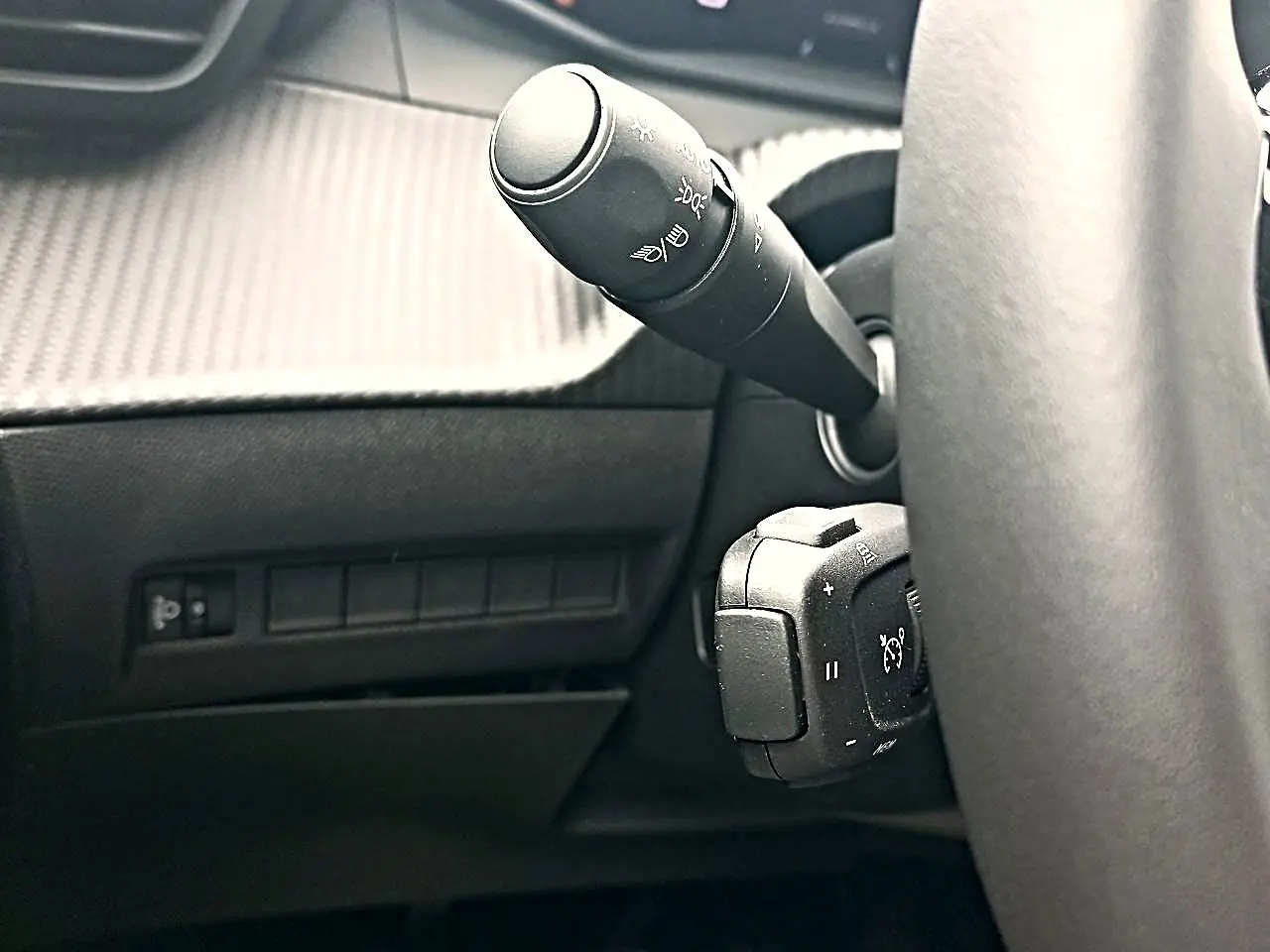 Gros plan sur la commande des phares et régulateur de vitesse derrière le volant d’un Peugeot 2008 1.2 100 allure.
