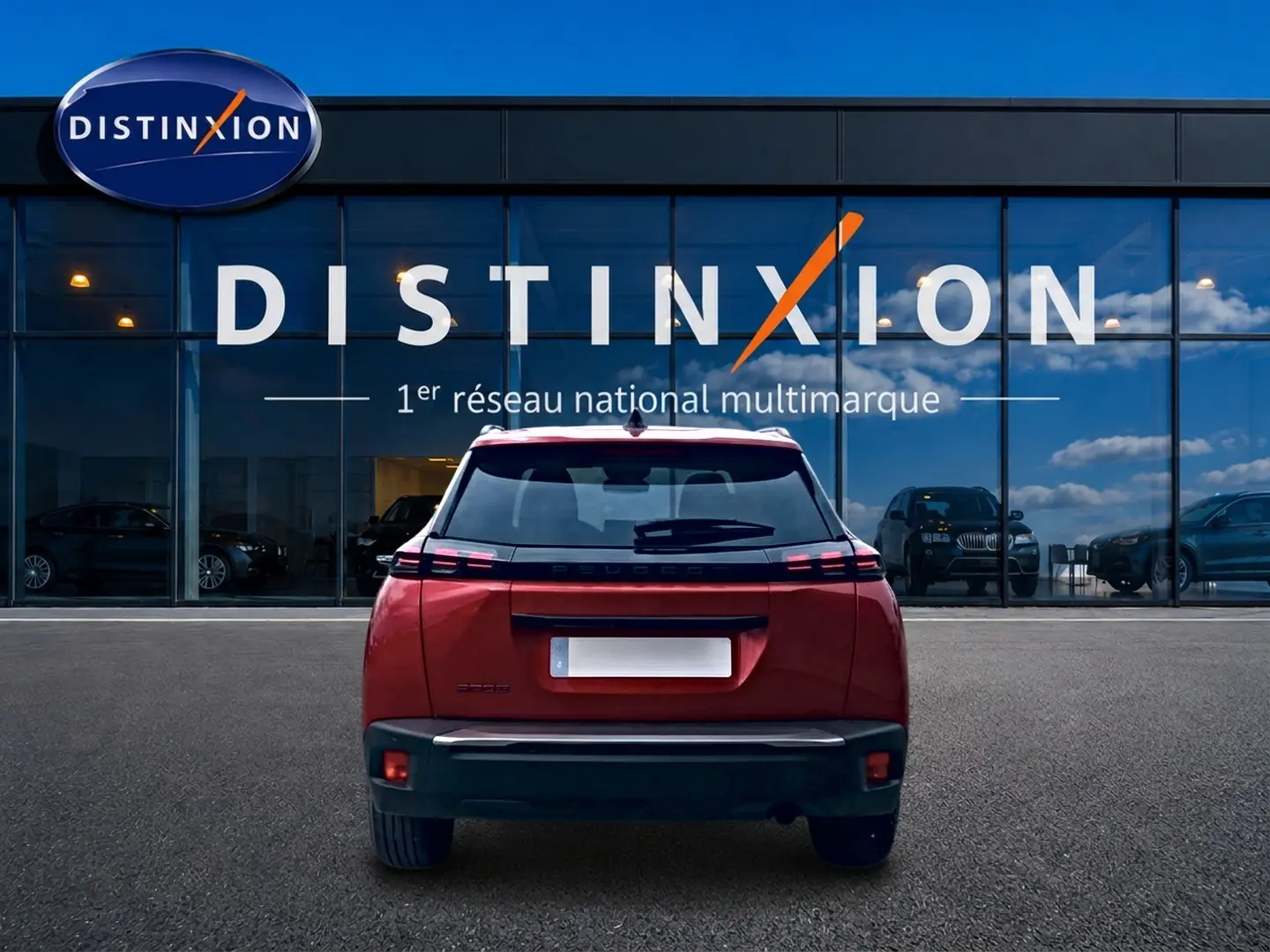 Vue arrière du Peugeot 2008 rouge Elixir 2025 avec feux LED distinctifs et becquet arrière, devant une vitrine Distinxion.