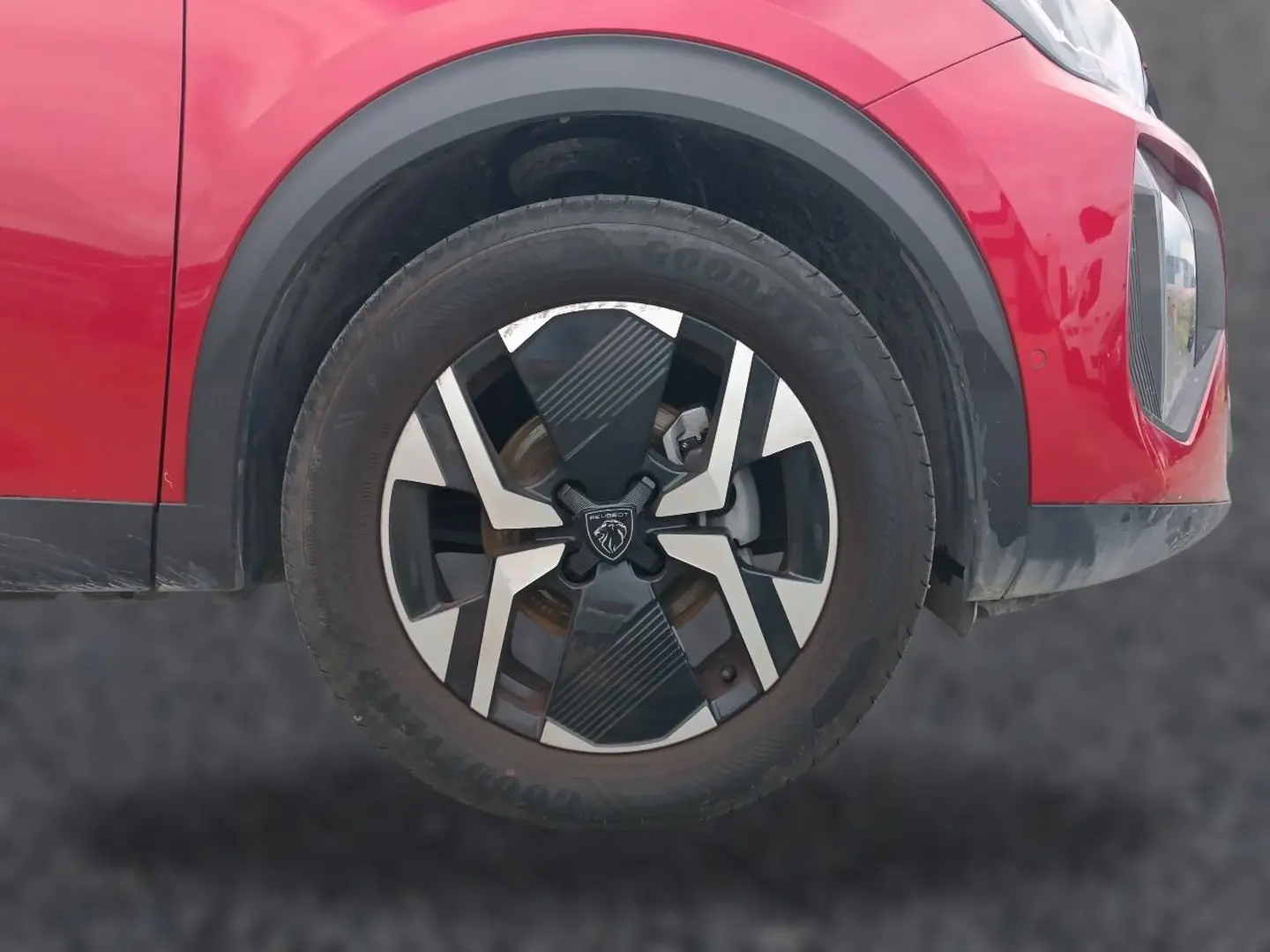 Gros plan sur la roue avant droite du Peugeot 2008 rouge elixir avec jante alu au design moderne.