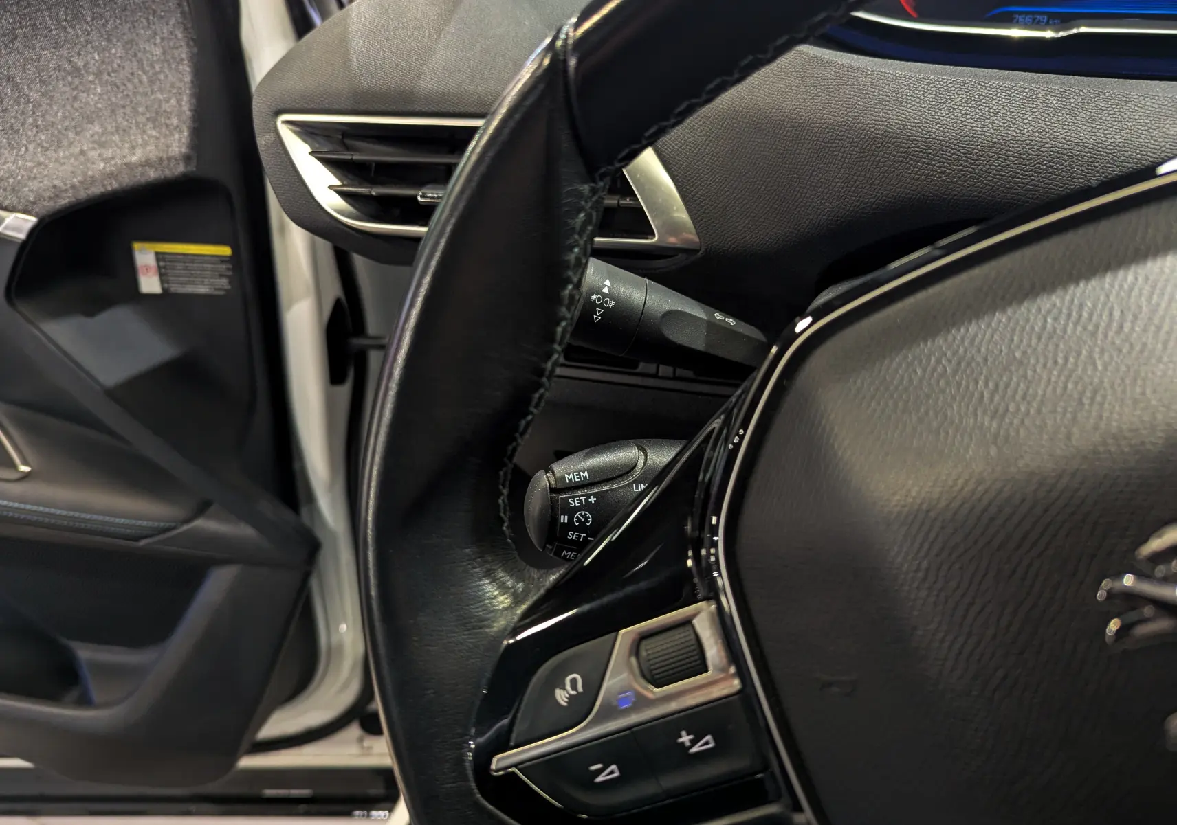 Vue rapprochée du volant noir et tableau de bord du Peugeot 3008 blanc Glacier avec porte avant gauche ouverte.