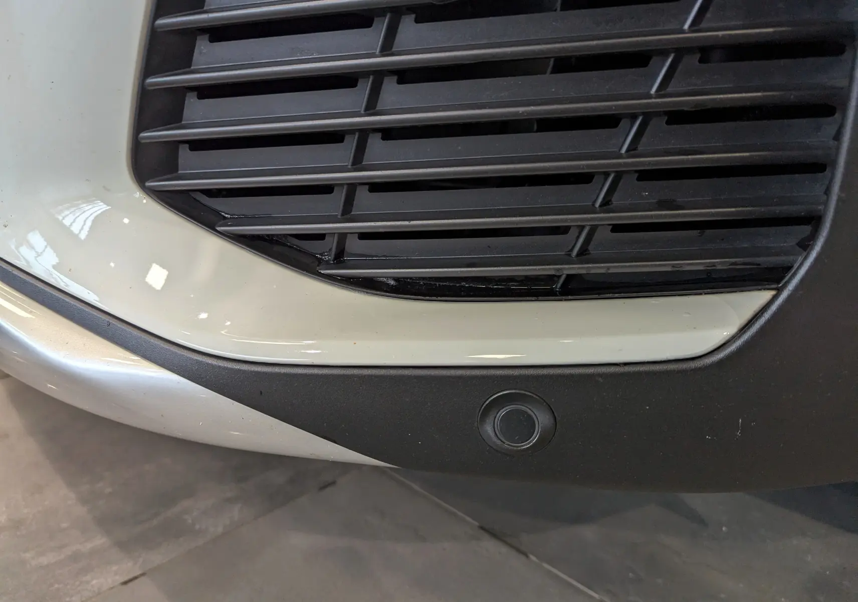 Gros plan sur la calandre avant droite blanche du Peugeot 3008 Crossway avec capteur de stationnement noir intégré.