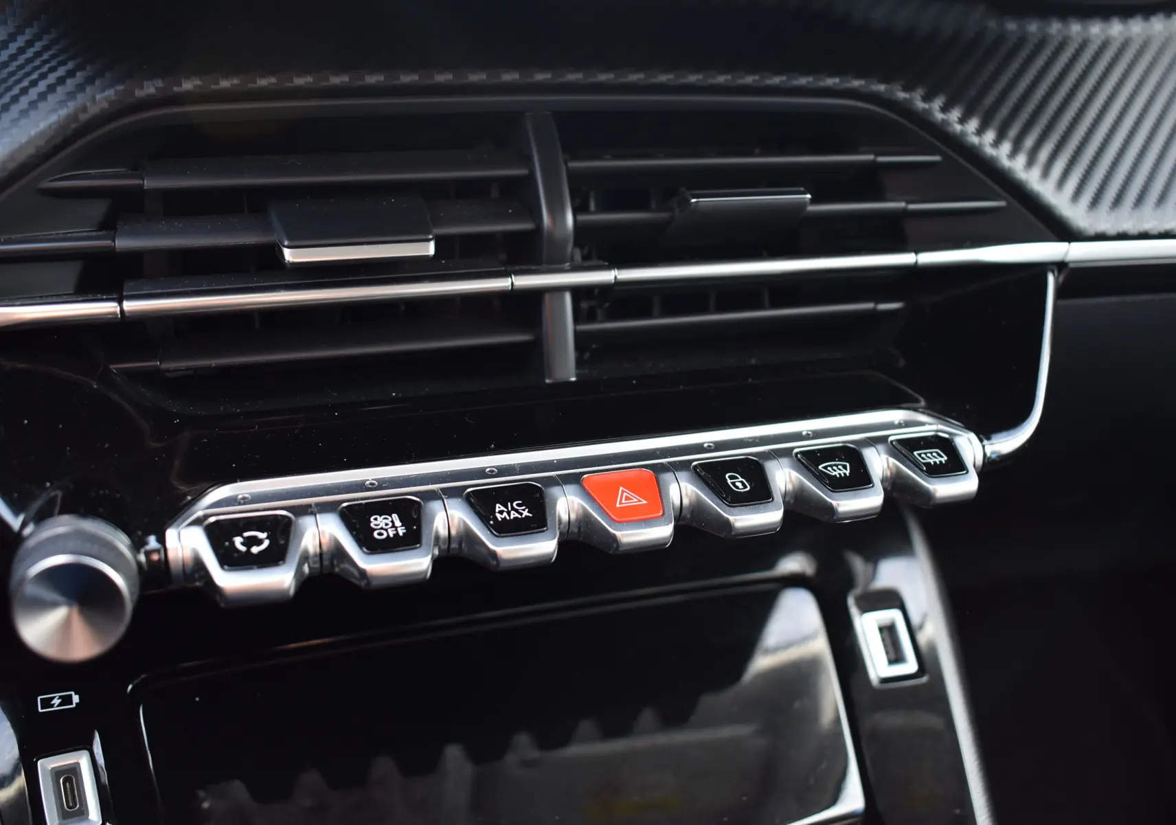 Gros plan sur la console centrale du Peugeot 2008 bleu 2021, mettant en valeur les commandes et aérateurs noirs brillants.