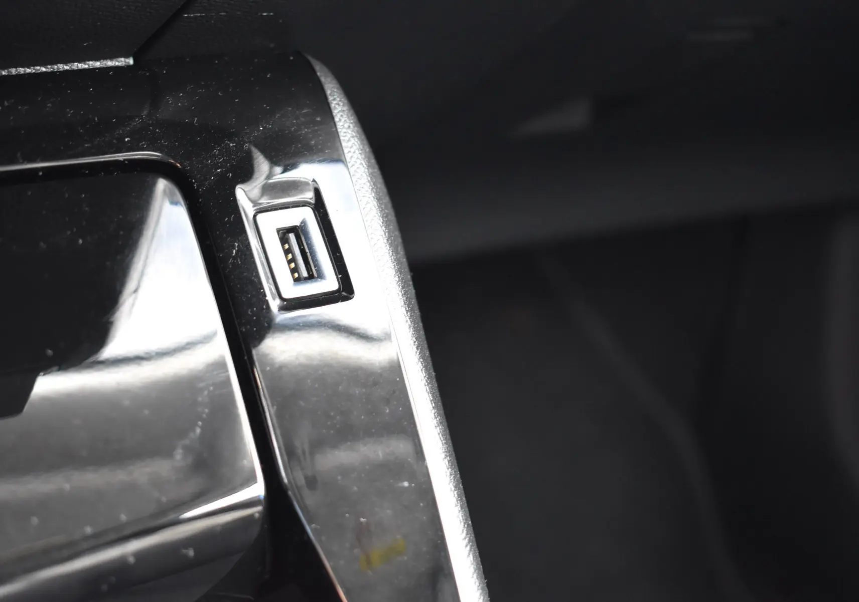 Gros plan sur un port USB intégré dans la console centrale noire brillante d'un Peugeot 2008 bleu 2021.