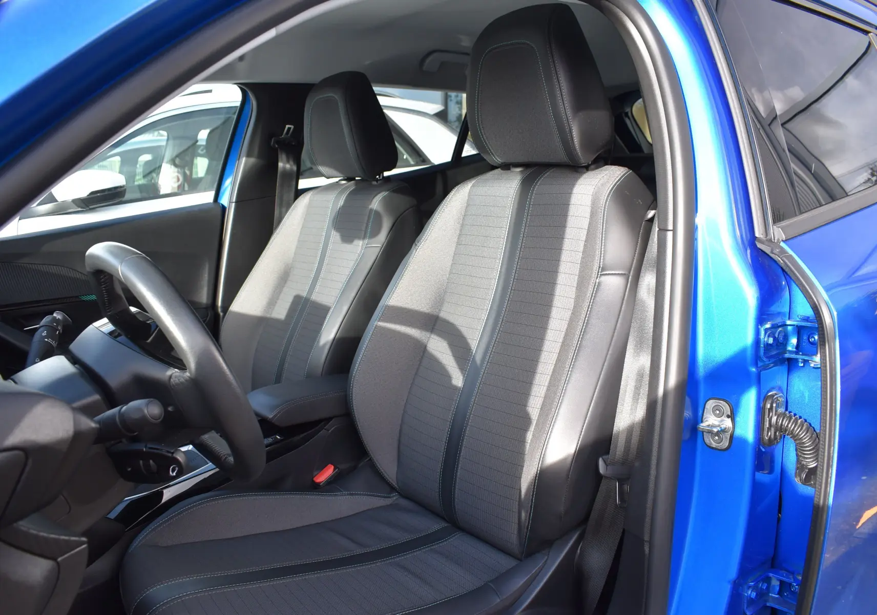 Intérieur du Peugeot 2008 bleu 2021, vue côté gauche sur les sièges avant en tissu et cuir avec surpiqûres contrastées.