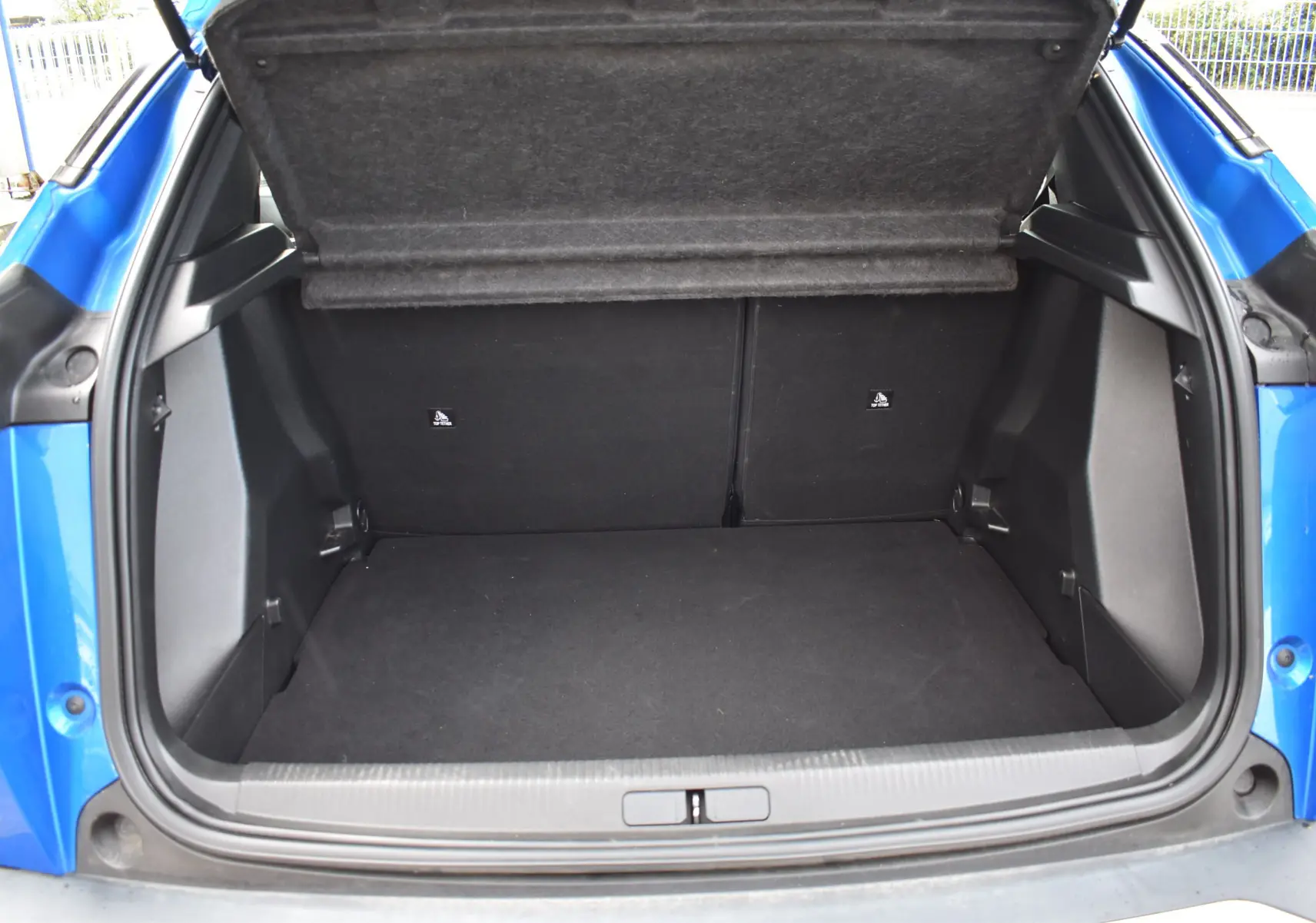 Coffre ouvert vu de l'arrière d'un Peugeot 2008 bleu 2021, version BlueHDi 110 Allure, montrant un espace de chargement vide.