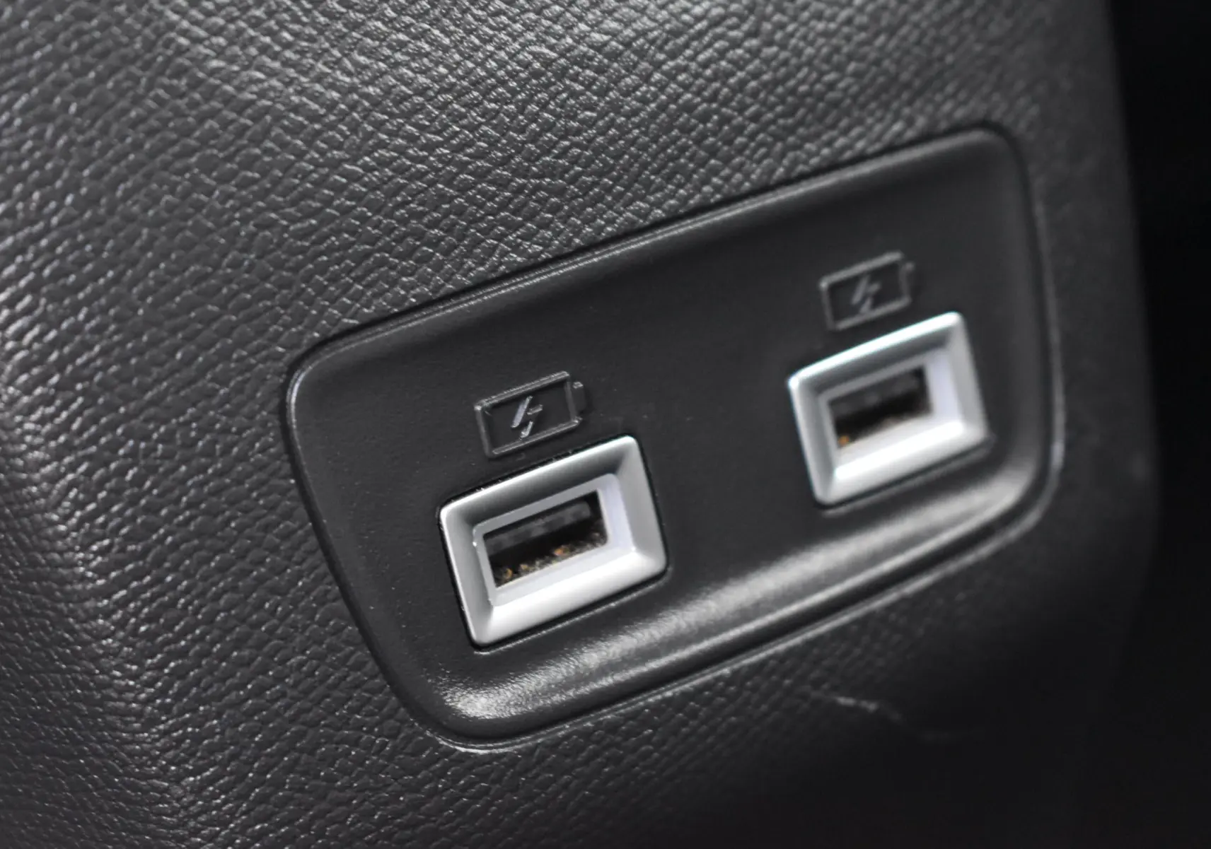 Gros plan sur deux ports USB de recharge situés sur une surface noire texturée à l'intérieur du Peugeot 2008 bleu.