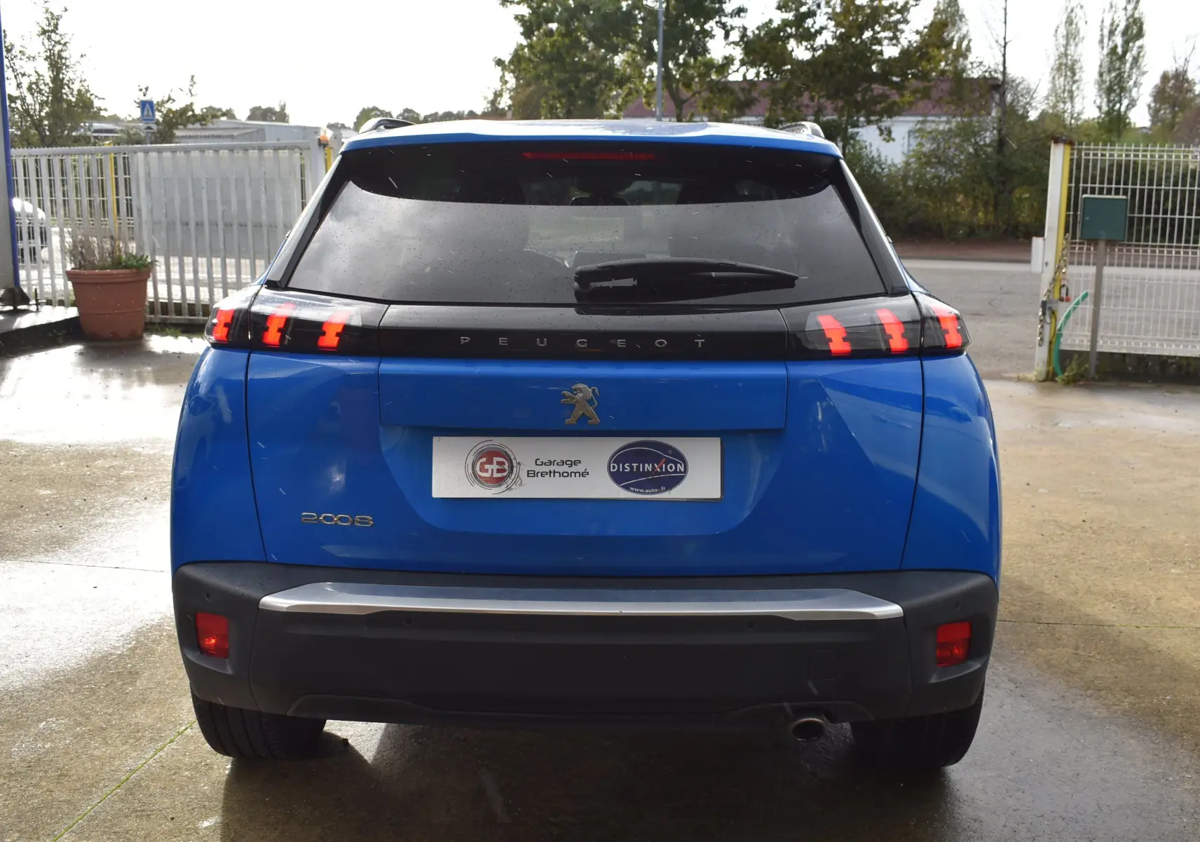 Vue arrière d'un Peugeot 2008 bleu 2021 avec feux arrière à griffes distinctives et lunette arrière teintée.