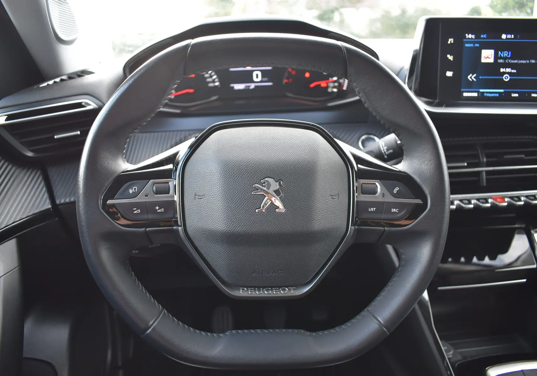 Vue rapprochée du volant cuir noir du Peugeot 2008 BleuHDI 110 2021 avec commandes intégrées et tableau de bord numérique.