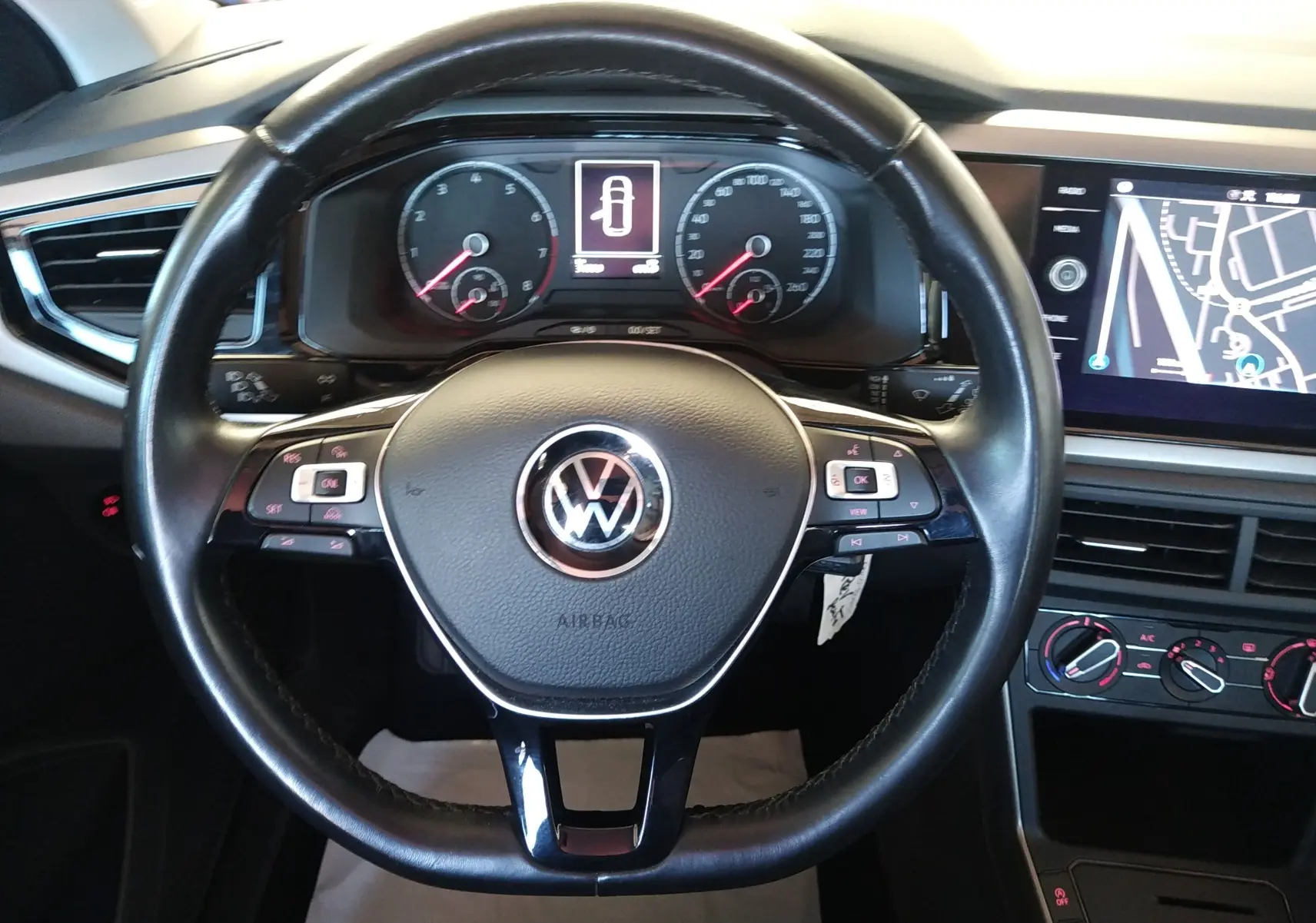 Vue rapprochée du volant noir de la Volkswagen Polo 2021 avec tableau de bord et écran GPS intégrés.