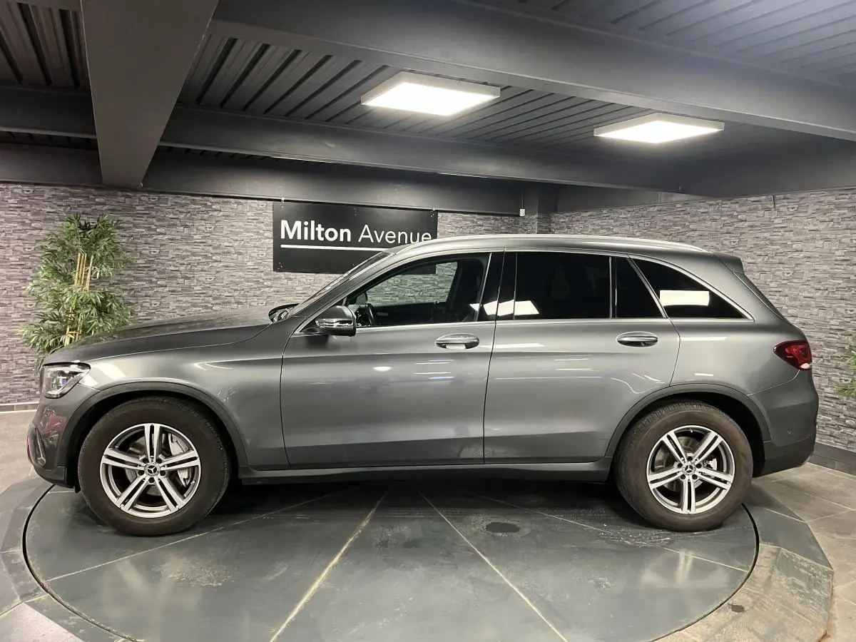 Vue latérale droite d'un Mercedes GLC gris métallisé avec jantes alliage 18 pouces dans un showroom intérieur.
