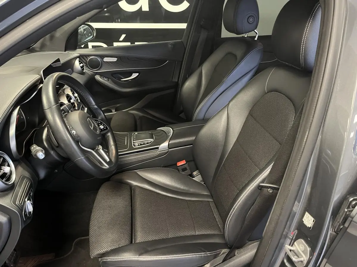 Intérieur côté conducteur d'une Mercedes GLC 200 gris, sièges noirs en cuir et console centrale visible.
