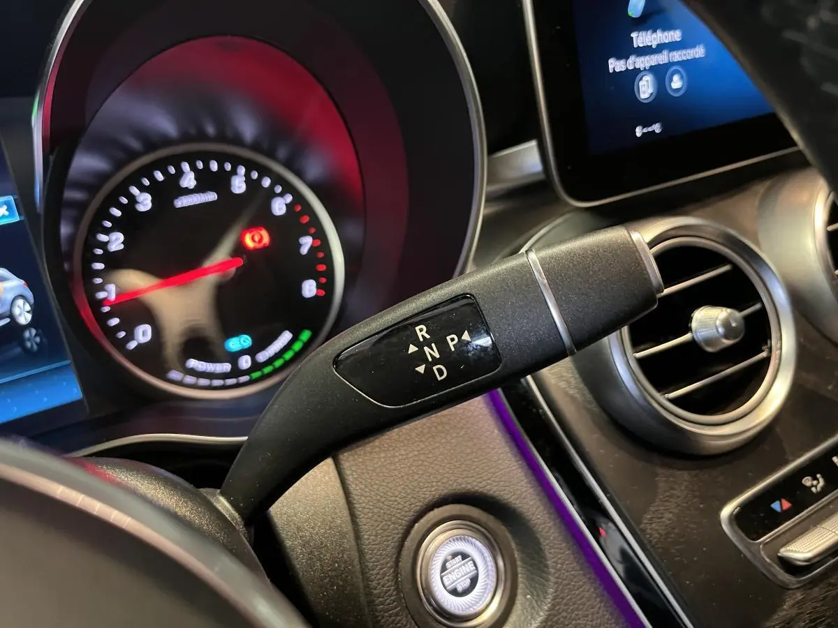 Gros plan sur la commande de boîte automatique et le tableau de bord du Mercedes GLC gris, avec affichage digital et ventilation ronde.