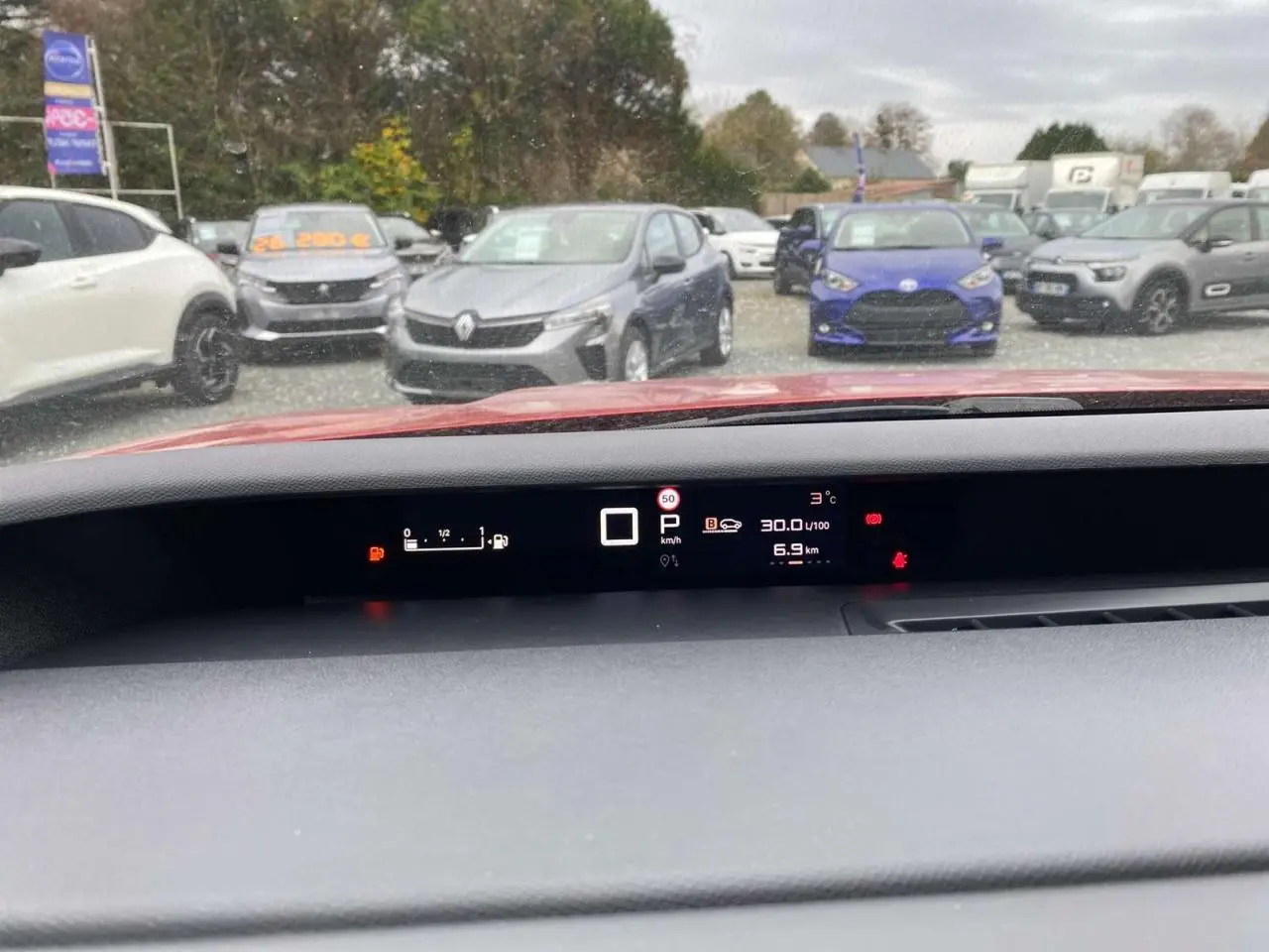 Vue du tableau de bord numérique d'une Citroën C3 Aircross rouge Elixir, affichage de vitesse et consommation.