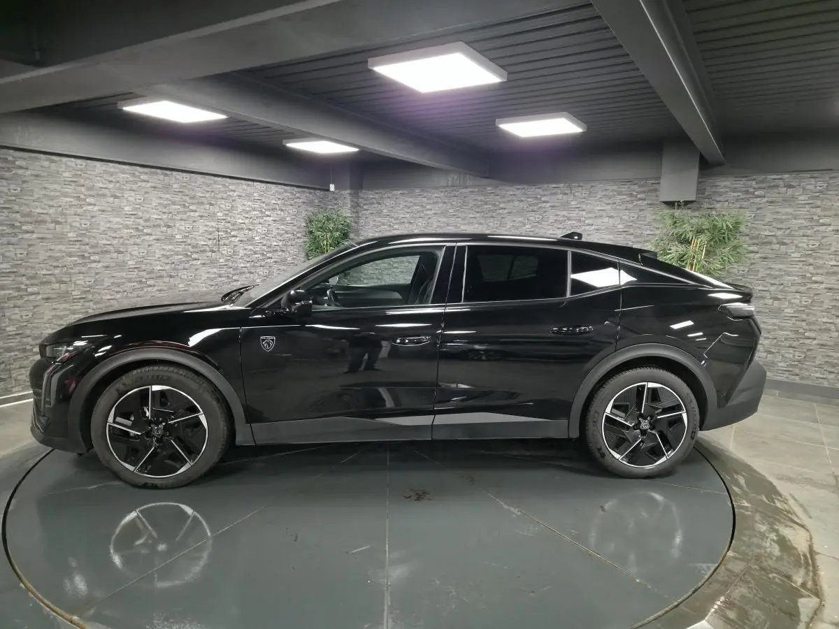 Peugeot 408 hybride noire vue de profil côté gauche, avec jantes alliage 19 pouces et toit plongeant.