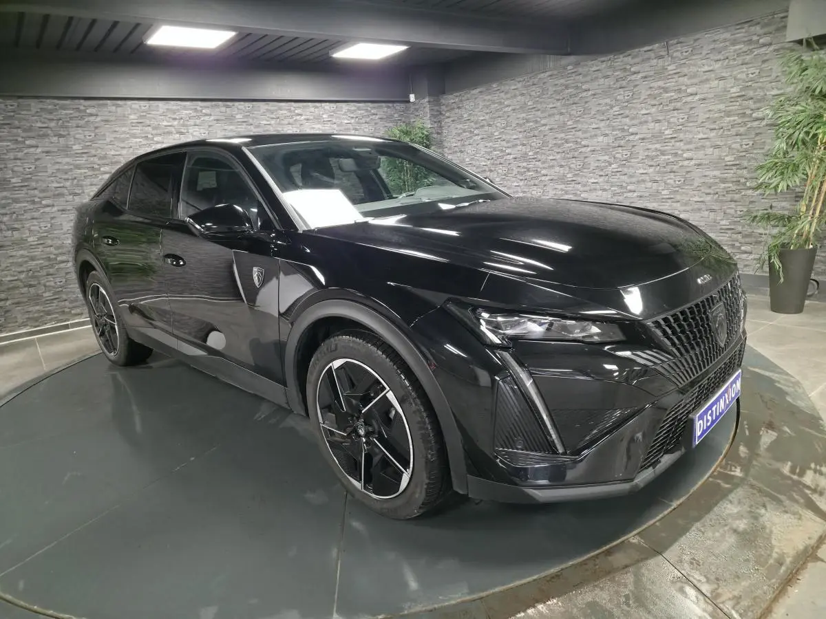 Peugeot 408 noire vue en 3/4 avant droit, avec calandre distinctive et jantes alliage 19 pouces diamantées.
