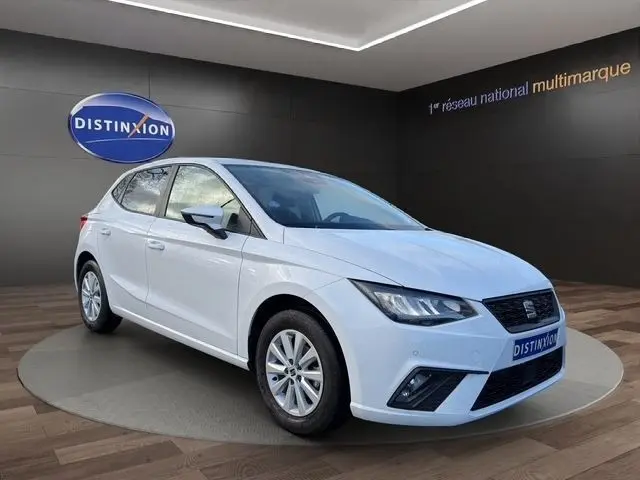 Vue 3/4 avant d'une SEAT Ibiza blanche 2023 avec vitres arrière surteintées dans un showroom.