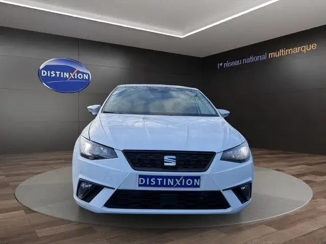 Vue frontale d'une SEAT Ibiza blanche 2023 avec vitres arrière surteintées, calandre noire et feux LED allumés.